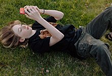 Teenager boy lying on grass using smartphone outdoors - 1 - IMAGO/Cavan Images