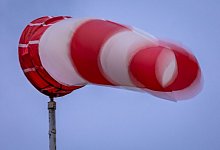 Windsack weht bei Regen und kräftigem Wind am Mast - Jens Büttner/dpa/dpa-tmn