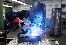 Eine Auszubildende zum Schweißer arbeitet einem Stück Metall - Oliver Berg/dpa/dpa-tmn