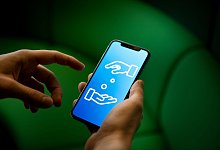 Ein Smartphone, auf dem Geldgeschäfte symbolisiert sind - Zacharie Scheurer/dpa-tmn