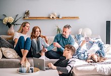 Familie unterh&auml;lt sich gemeinsam in einem Wohnzimmer - Zacharie Scheurer/dpa-tmn