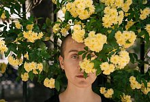 Eine Junge Frau hinter Blumen im Park - Yuliia Blazhuk/Westend61/dpa-tmn