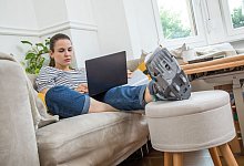 Eine Frau mit Fuß im Gips auf dem Sofa - Christin Klose/dpa-tmn