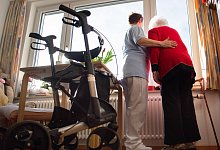 Eine Pflegerin und eine Heimbewohnerin an einem Fenster - Tom Weller/dpa