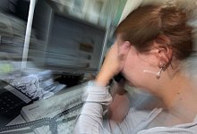 Eine Frau sitzt ersch&ouml;pft an ihrem Arbeitsplatz. - picture alliance / dpa