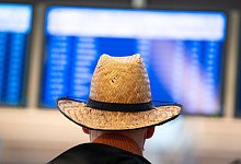 Ein Urlauber schaut auf die Abflugtafel in Hamburg. - Jonas Walzberg/dpa