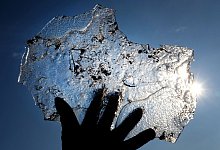 Eine Hand h&auml;lt eine Eisplatte vor blauem Himmel - Martin Gerten/dpa/dpa-tmn