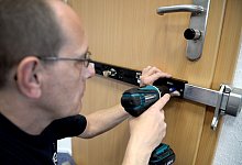 Montage eines Querriegelschlosses an einer Wohnungstür - Susann Prautsch/dpa-tmn