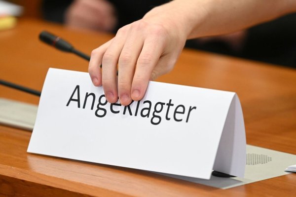 Ein Schild mit der Aufschrift "Angeklagter" wird auf die Gerichtsbank gestellt. - © Arne Dedert/dpa/Symbolbildarchiv