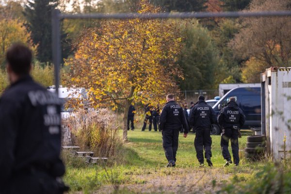 Polizisten stehen bei dem Großeinsatz auf einem Grundstück. (Archivbild) - © Christophe Gateau/dpa