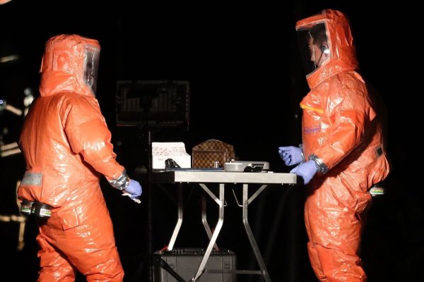 Feuerwehrleute untersuchen die Tasche mit dem undefinierten Stoff. - © David Young/dpa
