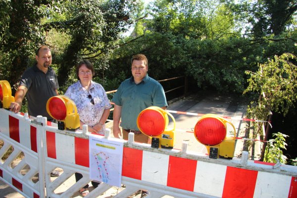 Kein Durchkommen mehr: Petra Wallbaum und ihr Sohn Niklas (rechts) an der gesperrten Brücke. Links Fachteamleiter Stadtentwässerung und Wasserwirtschaft Sven Anders. - © Wolfgang Becker