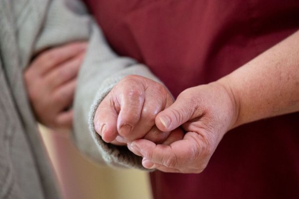 Eine Pflegekraft betreut in einem Seniorenhaus einen Bewohner. - © Marijan Murat/dpa