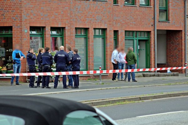 Polizisten und Passanten vor dem Haus am Tag der Tat. - © dpa