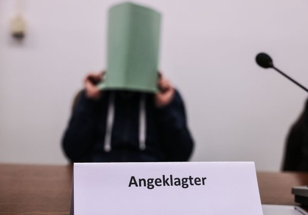 Der Angeklagte im Missbrauchskomplex Wermelskirchen hält sich im Gerichtssaal eine Mappe vor das Gesicht. - © Oliver Berg/dpa