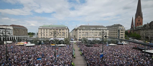 HSV-Fans stehen auf dem Rathausmarkt vor dem Hamburger Rathaus und feiern ihren Club. - © Christian Charisius/dpa