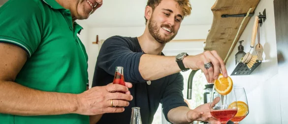 Freude am Experimentieren: Freunde bereiten in der heimischen Küche einen alkoholfreien Aperitif mit Sanbitter zu. Er ist für seine rote Farbe und bittersüße, herbe Geschmacksnote bekannt. - © Christin Klose/dpa-tmn