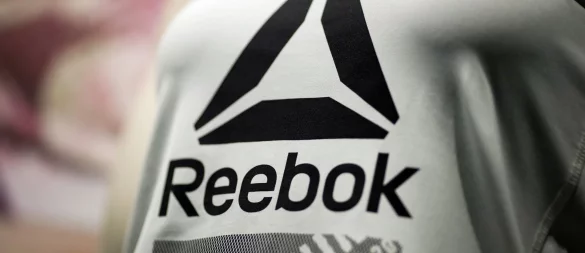 Das Reebok-Logo auf einem Shirt. (Archivbild) - © Daniel Karmann/dpa