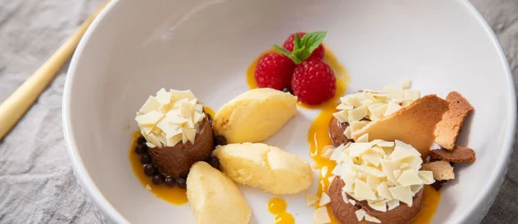 Dessert-Teller mit Schokoladen- und Mango-Mousse auf Mangopüree. Getoppt wird alles mit Eiswaffelsplittern, Schokoraspeln, Himbeeren und Minzblättern. - © Christin Klose/dpa-tmn