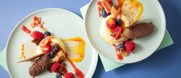 Sieht aus wie ein Bagel aus Eis: In sogenannte Savarin-Formen wird das Mangoeis gefüllt und gefroren. Die Mitte wird mit Fruchtigem gefüllt, dazu einen Klecks Schokoladenmousse, Mango- und Erdbeerpüree drunter und drüber streichen. - © Christin Klose/dpa-tmn