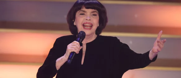 Mit Chanel-Hut und chinesischem Sonnenschirm schützt Chanson-Legende Mireille Mathieu ihre Haut. (Archivbild) - © Bodo Schackow/dpa