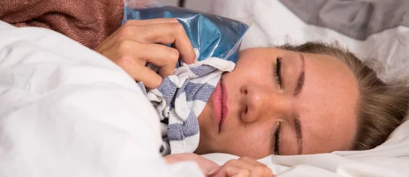 Wenn der Zahn einem die Nachtruhe raubt, kann ein Kühlpack im Tuch Linderung verschaffen. - © Christin Klose/dpa Themendienst/dpa-tmn