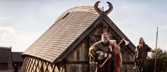 Zeitreise: Als Wikinger verkleidete Schauspieler stehen vor der Königshalle im «Land der Legenden». - © Sagnlandet Lejre/Visit Fjordlandet/dpa-tmn