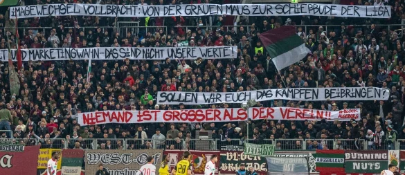 Die Augsburger Fans üben auf Spruchbändern Kritik am Weg der Vereinsführung mit Sandro Wagner. - © David Inderlied/Kirchner-Media/dpa