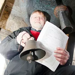 Klare Regeln: Mit einem Mini-Exemplar fürs Pressefoto und der Läuteordnung in den Händen kniet Pfarrer Rolf-Joachim Krohn-Grimberghe unter einer der drei St.-Nicolai-Glocken. Foto: Backe