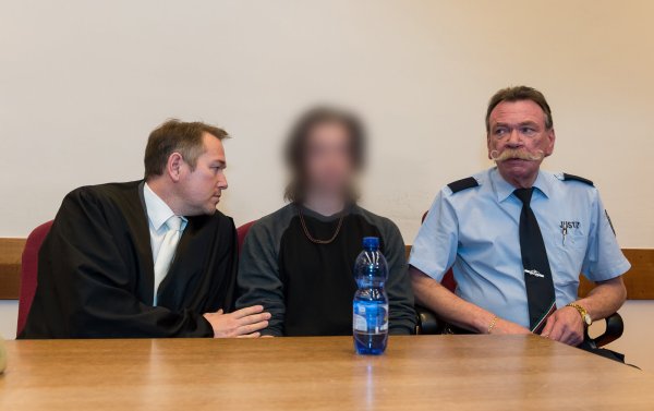 Die Anklage wirft dem 22-Jährigen (M) vor, seine 31 Jahre alte Freundin im Juni 2016 mit Messerschnitten in den Hals getötet zu haben. Anwalt Carsten Ernst (l) und einem Justizbeamten (r). - © Guido Kirchner/dpa
