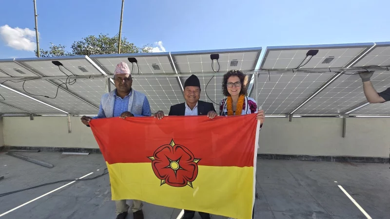 Die Photovoltaikanlage steht: Die nepalesischen Gastgeber und ihre G&auml;ste aus Detmold pr&auml;sentieren davor stolz die lippische Fahne. - &copy; Foto: Stadt Detmold