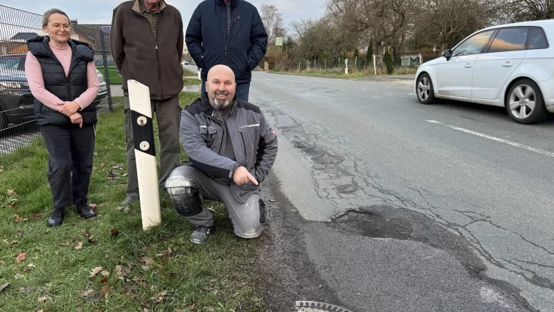 Susanna Radic, Dirk Brinkmann, Detlef Wunderlich (von links) sowie Niko Radic (knieend) an der viel befahrenen Sorrenheider Stra&szlig;e, an der sich zahlreiche Schlagl&ouml;cher und Unebenheiten befinden. - &copy; Sandra Castrup