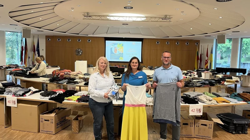 Margit Monika Hahn (links), Miriam Sch&auml;fer und Tobias Pri&szlig; pr&auml;sentieren einige der zu tauschenden Kleidungsst&uuml;cke im Kreistagssitzungssaal. - &copy; Kreis Lippe