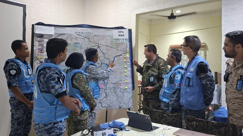 Lage der Konfliktparteien: Der malaysische Offizier weist Oberstleutnant Stefan und das Beobachterteam mit der Karte in die aktuelle Situation ein. - &copy; Bildrechte: Bundeswehr