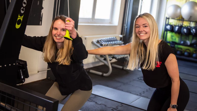 Nicole Serr, stellvertretende Studioleiterin bei Fitness First in Detmold, demonstriert unter Anleitung von Studioleiterin Svenja Eikermann das Training am Ski-Ergometer, das beim Hyrox-Training zum Einsatz kommt. Der Mix aus funktionellem Kraft- und Ausdauersport ist bei den Fitness First-Mitgliedern aktuell besonders beliebt. - &copy; Raphael Bartling
