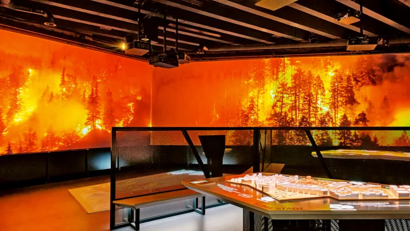 Klimaereignisse können in der Klimaerlebniswelt spürbar miterlebt werden. Wenn auf der Leinwand ein Waldbrand tobt, wird es auch im Raum erheblich wärmer. Nach einigen Minuten setzt dann wieder eine Abkühlung ein. Foto: Red Dot - © Red Dot