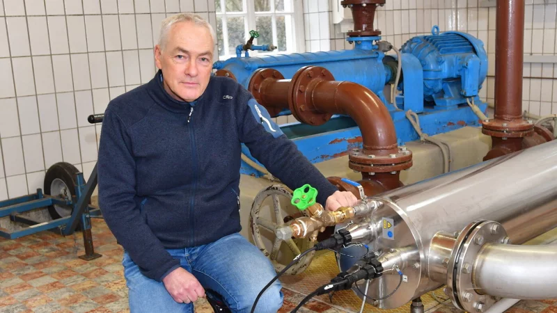 Wassermeister Olaf Frigge kniet im Pumpenh&auml;uschen an der Schopke neben der Pumpe, in der das Wasser in dem Edelstahlrohr mit UV-Licht bestrahlt wird, um eventuell vorhandene Bakterien abzut&ouml;ten. - &copy; Gunter Held