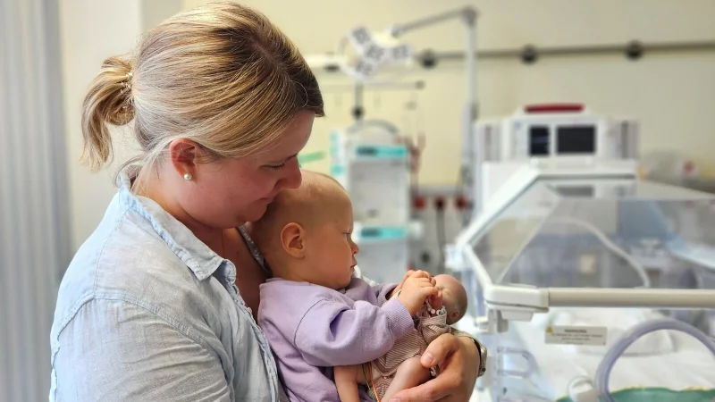 Der 16 Monate alte Junge h&auml;lt eine Fr&uuml;hchenpuppe in den H&auml;nden, die etwa so gro&szlig; ist wie er damals bei der Geburt. - &copy; Irma Mujanovic/MKK