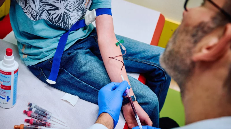 Ein Arzt nimmt bei einem Patienten eine Blutprobe. - © picture alliance/dpa