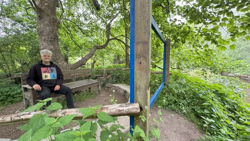 Ulrich Kaminsky sitzt auf der "Bank zum Werreblick" im "Recyclinggarten" auf dem Gelände des UWZ, rechts verläuft die Werre. - © Sven Kienscherf