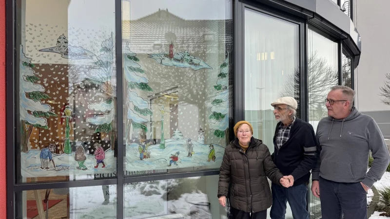 Karolinenheim-Bewohnerin Gisela Becker, K&uuml;nstler Bernt Ziegler und Einrichtungsleiter Harm-Hendrik M&ouml;ller (von links) vor der winterlichen Landschaft auf den Fenstern im Eingangsbereich. - &copy; Sandra Castrup