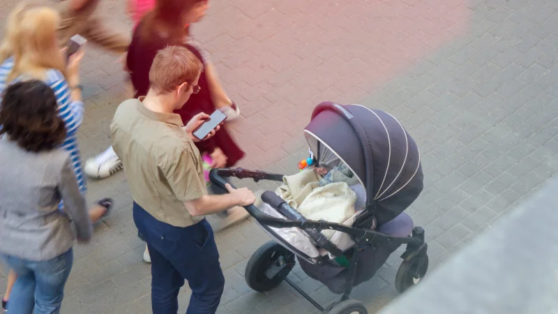 Die Blicke gelten Instagram und Co. statt dem Baby im Kinderwagen: Das kann fatale Folgen für die Bildung einer stabilen Eltern/Kind-Beziehung haben. - © SVIATLANA - stock.adobe.com