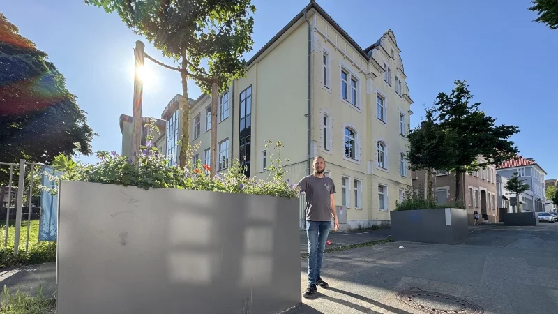 Benjamin Reichardt steht an den Blumenkübeln, die unmittelbar am Haupteingang zur Grundschule Kirchplatz an der Schülerstraße platziert sind. - © Sven Kienscherf