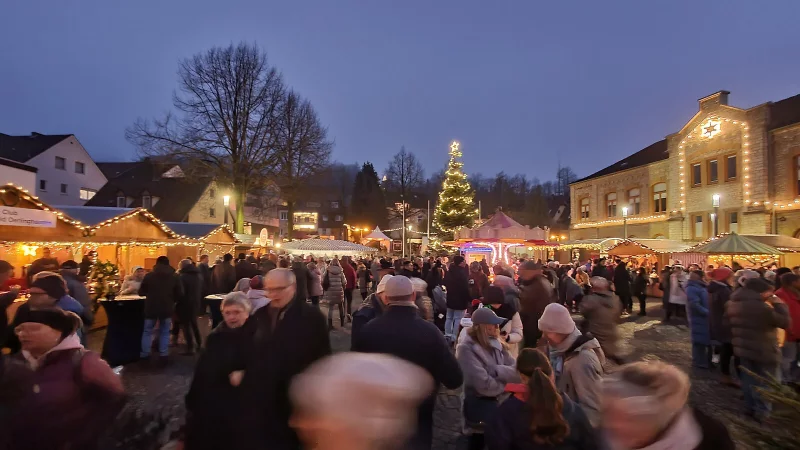 Besucher genießen die festliche Atmosphäre auf dem Oerlinghauser Weihnachtsmarkt mit beleuchtetem Weihnachtsbaum und bunten Marktständen. - © VVV