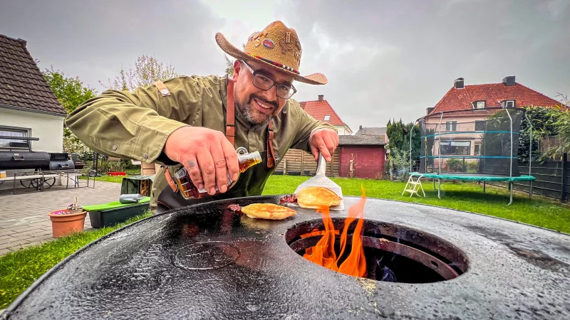Nur echt mit Cowboy-Hut: Hawk Blackburn aus Herford ist gebürtiger US-Amerikaner und BBQ-Profi durch und durch. Bei ihm landen nicht nur Fleisch und Gemüse auf dem Grill, sondern auch Pancake-Bacon-Sticks mit Ahornsirup. Und die sind megalecker! - © Daniel Salmon