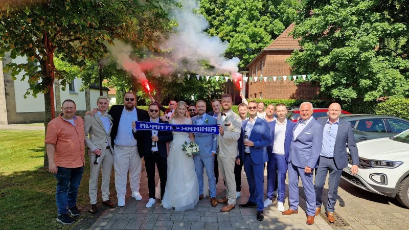 Fu&szlig;ballverr&uuml;ckte Familie und Freunde stellen sich nach der Trauung von Kristin und Ren&eacute; Prehn zum Foto auf &ndash; sie k&ouml;nnen nicht nur die frisch Verm&auml;hlten feiern, sondern auch den ebenso frischen Aufstieg des DSC Arminia. - &copy; Oliver Prehn