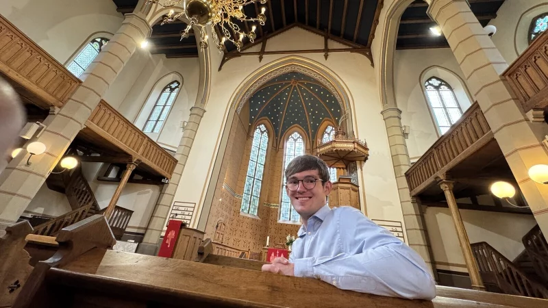 Tim Alexander sitzt in der Kilianskirche, im Hintergrund sieht man den Sternenhimmel im Altarraum. - © Sven Kienscherf