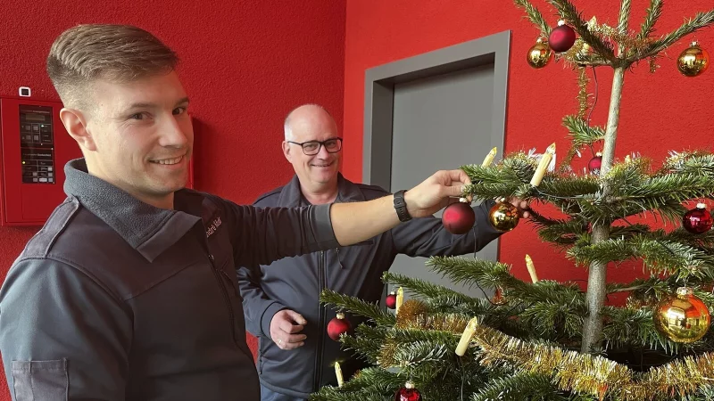 An Heiligabend m&uuml;ssen Jens Kluge (rechts) und Andr&eacute; K&ouml;ster sich trotz Besinnlichkeit jederzeit auf einen Einsatz einstellen. Viel Weihnachtsdeko gibt es auf der Bad Salzufler Feuerwehr nicht. Der Tannenbaum im Eingangsbereich ist jedoch Pflicht und wird gemeinsam geschm&uuml;ckt. - &copy; Daniel Hobein