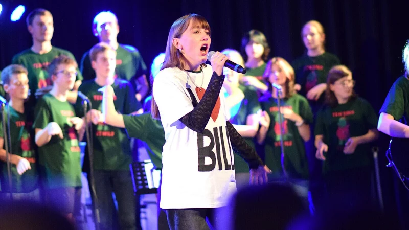 W&auml;hrend der Show treten immer wieder Solistinnen und Solisten auf. Im Hintergrund begleitet der Chor in den zum Abend passenden gr&uuml;nen Shirts die Auftritte. - &copy; Karin Prignitz