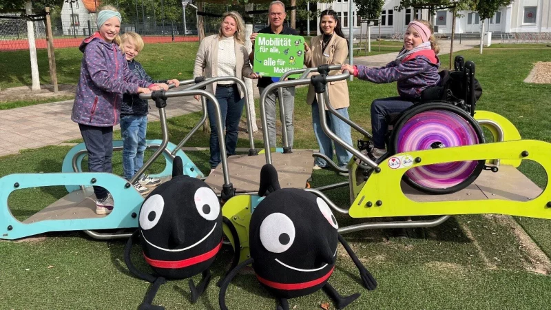 Mathilda (rechts) und ihre Geschwister Jonathan und Antonia (links) sind begeistert &uuml;ber die neue Inklusionswippe im B&uuml;rgerpark Lage. Mit den Kindern freuen sich (von links) Luba Schmidt und Uwe Friedrichsmeier vom Fachteam Stra&szlig;en, Sportpl&auml;tze, Friedh&ouml;fe und Werksstudentin S&uuml;eda Bozdayi. - &copy; Stadt Lage